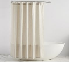 a white bath tub sitting next to a shower curtain on top of a tiled floor