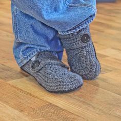 a person standing on top of a wooden floor wearing crocheted slippers and jeans