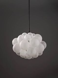 a white light hanging from a black ceiling with lots of balloons in the shape of clouds