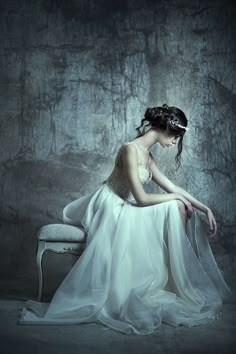 a woman in a white dress sitting on a chair