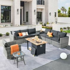 an outdoor living room with grey couches and orange throw pillows on the patio area