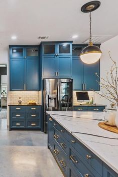 a large kitchen with blue cabinets and marble counter tops, along with an island in the middle