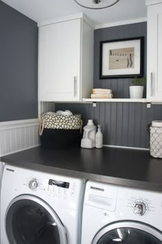 a washer and dryer in a small room with white cabinets, black counter tops and gray walls