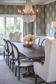 a dining room table with white chairs and a chandelier hanging from the ceiling