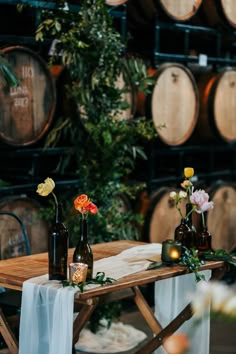 two wine bottles are sitting on a table with flowers and candles in front of them