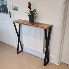 a plant is sitting on top of a wooden table in front of a white door