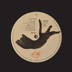 the label for love trip's album, featuring a black cat laying on its back