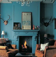 a living room filled with furniture and a fire place in front of a blue wall