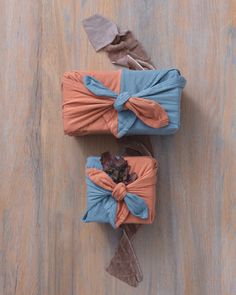 two wrapped presents sitting on top of a wooden floor next to each other with bows