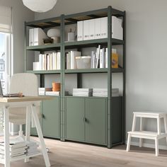 a room with a desk, chair and bookshelf next to a large window