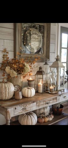 a table topped with lots of white pumpkins next to a window filled with candles