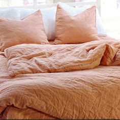 an unmade bed with peach colored linens and pillows