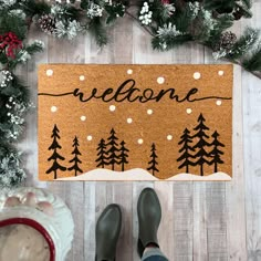 someone standing in front of a welcome mat with pine trees and snowflakes on it