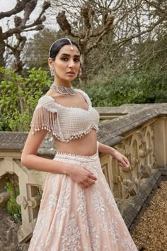 This lehenga set features delicate embroidery in pearls, bugle beads, and crystals. The full-worked blouse shows an exaggerated pearl tassels. It is paired with a matching embroidered organza dupatta with pearl drops.From Seema Gujral's A Royal Affair collection. DELIVERY TIMEPlease allow 8-12 weeks for your outfit to arrive. FABRIC DETAILSLehenga & Blouse - Raw SilkDupatta - Organza Professional cleaning only. White And Peach Lehenga, Crystal Blouse Design, Blouse Designs Beads Work, Pearl Blouse Saree, Peach Blouse Design, Blouse Designs Latest For Lehenga, Beads Blouse Design, Pearl Work Blouses, Pearl Work Blouse Designs