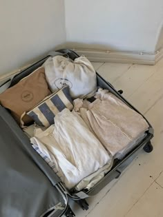 an open suitcase filled with clothes on top of a hard wood floor next to a wall