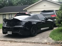 a black sports car parked in front of a house with its hood up and the trunk open