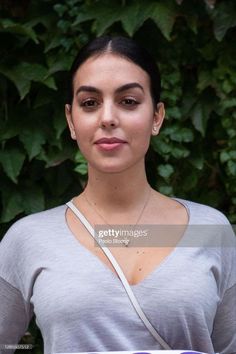 a woman in grey shirt holding a plate with food on it and looking at the camera