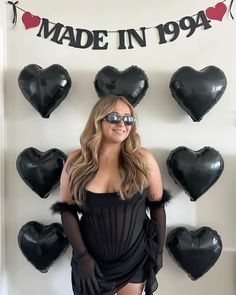 a woman standing in front of black heart shaped balloons