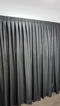 a black curtain is hanging in front of a white wall and carpeted flooring