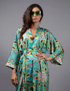 The Nuvula Psychedelic Stars Teal Long Satin Kimono can be worn to lounge, overtop a slip dress for a night out, and pairs perfectly with a matching bikini and flared pants for working out or hanging out by the pool. Timeless style and creativity meet Psychedelic designs in Nuvula’s handmade silk kimonos. This Limited Edition Robe is handcrafted in super soft satin. Wear it to elevate an evening dress with high stiletto heels, slip it on over a swimsuit, or wear it at home as nightwear. Hand-Mad Summer Sleepwear Kimono With Prints, Green Kimono Sleeves Sleepwear For Summer, Green Summer Sleepwear With Kimono Sleeves, Multicolor Summer Sleep Kimono, Teal Kimono, Pool Wear, Satin Kimono, Duchess Satin, Boho Kimono