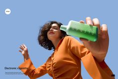 a woman in an orange shirt is drinking from a green water bottle with the word energy written on it