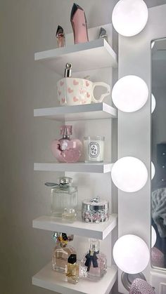 a white shelf filled with lots of different items next to a mirror and light fixture