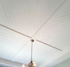 a chandelier hanging from the ceiling in a room with white walls and wood paneling