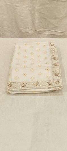 a white table cloth on top of a bed with an embroidered border around the edges