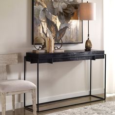 a black console table with two lamps and a painting on the wall