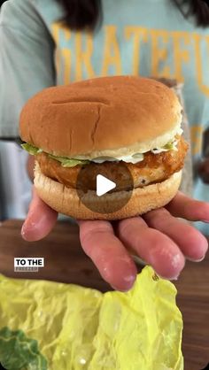 a person holding a hamburger in their hand with the caption to the video below