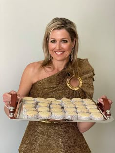 a woman in a gold dress holding a tray of cookies