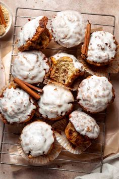 cinnamon muffins with icing and cinnamon sticks on a cooling rack