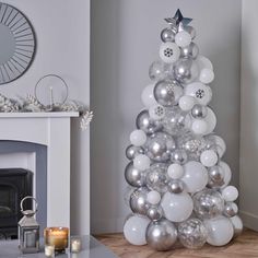 a christmas tree made out of balloons in a living room next to a fire place