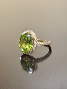 DeKara Designs Collection Our latest design! An elegant and lustrous Peridot Halo Diamond Engagement Ring. Metal- 18K Yellow Gold, .750. Stones- Oval Natural Peridot 11.6 MM x 9.4 MM 4.16 Carats, 44 Round Diamonds F-G Color VS1-VS2 Clarity 0.46 Carats. Latest of my creations! A Beautiful Peridot Diamond Halo Engagement Ring Made in 18K Yellow Gold. There is a beautiful genuine green peridot in the center of the ring that is professionally set in between four double prongs. The peridot is a beaut Peridot And Diamond Rings, Formal Peridot Diamond Ring In Yellow Gold, Yellow Gold Tsavorite Ring With Halo Setting, Yellow Gold Rings With Tsavorite In Halo Setting, Luxury Oval Peridot Rings, Elegant Peridot Diamond Ring, Luxury Peridot Jewelry With Accent Stones, Oval Peridot Diamond Ring For Formal Occasions, Luxury Tsavorite Rings With Halo Setting