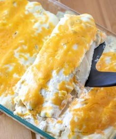 a casserole dish with chicken and cheese in it being spooned out by a spatula