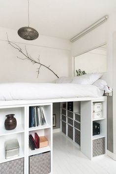 there is a bed that has been built into the wall with shelves below it and a mirror above it