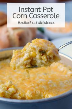 a spoon full of corn casserole on top of a blue bowl with bread in the background