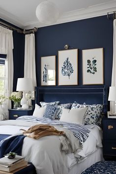 a bedroom with blue walls and white bedding, two framed pictures on the wall