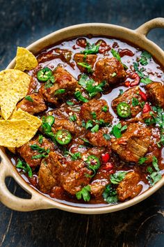 a bowl filled with meat and salsa next to tortilla chips