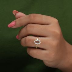 a woman's hand holding a ring with a diamond in the middle and a green background