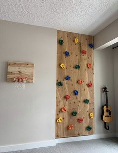 there is a rock climbing wall in the room with a guitar on the floor next to it