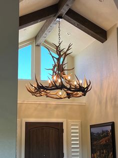 an antler chandelier hangs from the ceiling in front of a door and window