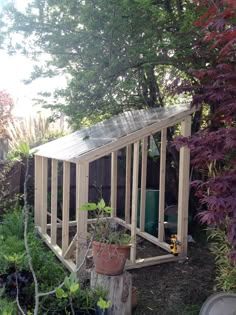 a small wooden shed sitting in the middle of a yard with potted plants on it