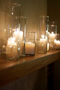 candles are lined up on a mantle with glass vases