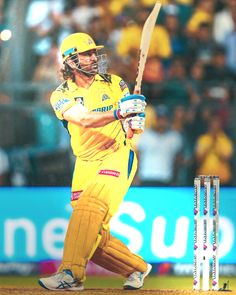 a man swinging a bat at a ball during a cricket game in front of a crowd