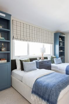 two twin beds in a bedroom with blue and white decor on the walls, along with bookshelves