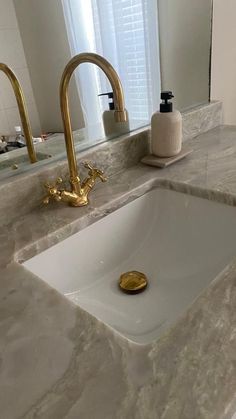 a bathroom sink with gold faucet and marble counter top