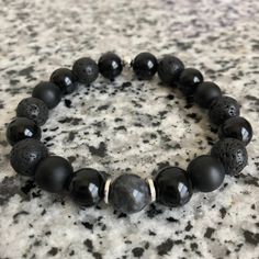 Lava Stone, Matte Black Onyx, And Onyx 10mm Bracelet w/ Silver Accents Mixed, matched, and designed with a variety of elegant beads for a graceful look. This is a beautiful piece made to be worn separately or combined with our other Embody'd Art pieces! This bracelet can also be worn as an oil diffuser. Just add one drop of your favorite oil to the AAA grade lava beads and you're set to go. This bracelet is crafted with quality elastic stretch cord. This bracelet is also designed to fit snug on Black Beaded Bracelets For Gifts, Adjustable Obsidian Stretch Bracelet With Round Beads, Adjustable Black Gemstone Beaded Bracelets, Black Beaded Wristband As Gift, Adjustable Black Bracelet With Round Beads, Adjustable Black Round Bead Bracelets, Adjustable Black Jewelry With 8mm Beads, Adjustable Black Wristband With Round Beads, Adjustable Black Wristband With 8mm Beads