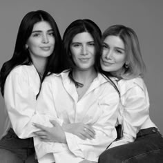 three women are posing for the camera with their arms around each other and one woman is sitting on her lap