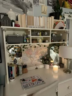 a white desk topped with a lamp next to a book shelf filled with lots of books